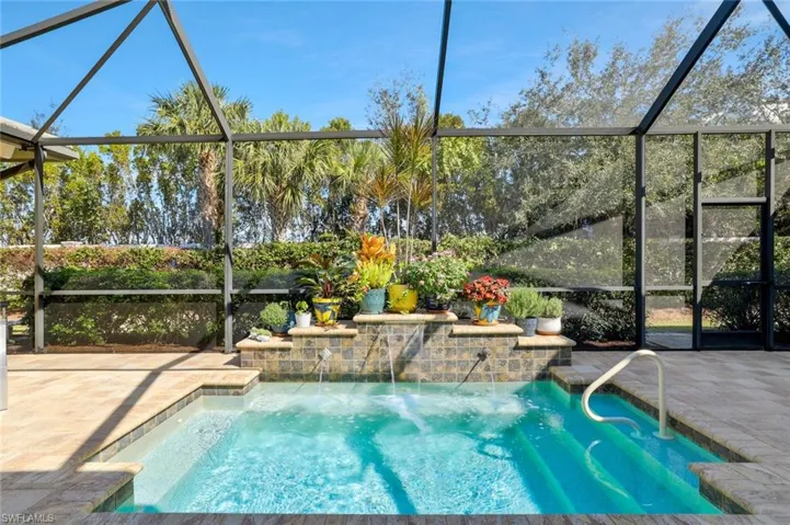 Huge Spa with Water Feature Graces the outdoor living with Outdoor Kitchen and Gorgeous Flowers in Pots to enhance the Lanai