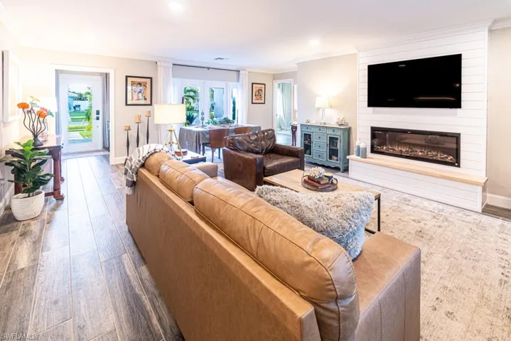 Living area featuring baseboards, a fireplace, wood finished floors, and ornamental molding