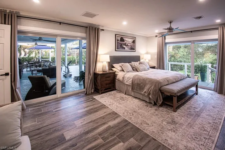 Bedroom with access to exterior, visible vents, wood finished floors, and ornamental molding