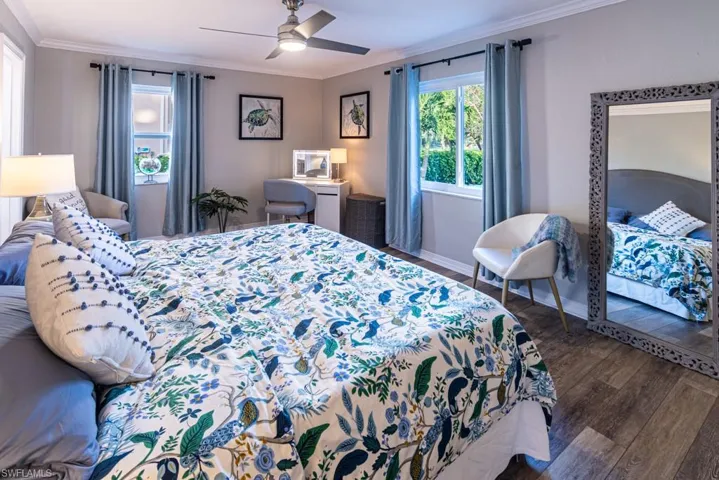 Bedroom with baseboards, a ceiling fan, wood finished floors, and crown molding
