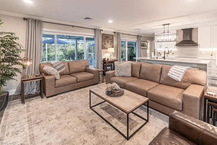 Living area with ornamental molding, visible vents, and recessed lighting