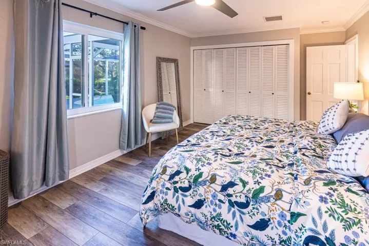 Bedroom featuring crown molding, baseboards, dark wood-style floors, ceiling fan, and visible vents