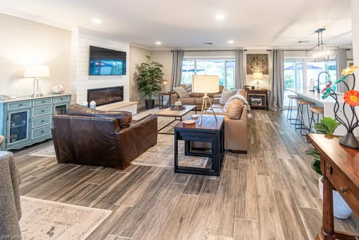 Living area with wood finish floors, crown molding, a fireplace, and recessed lighting