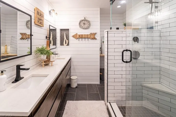 Full bath with double vanity, a sink, and a shower stall