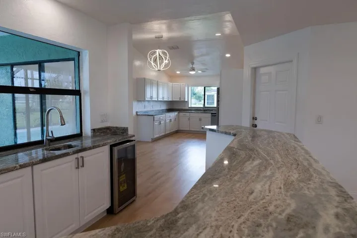 Bar with pendant lighting, wine cooler, and white cabinetry