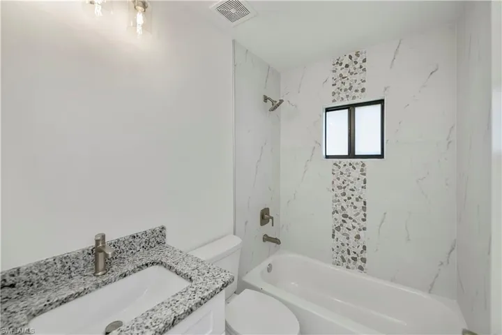 Full bathroom with vanity, toilet, and tiled shower / bath