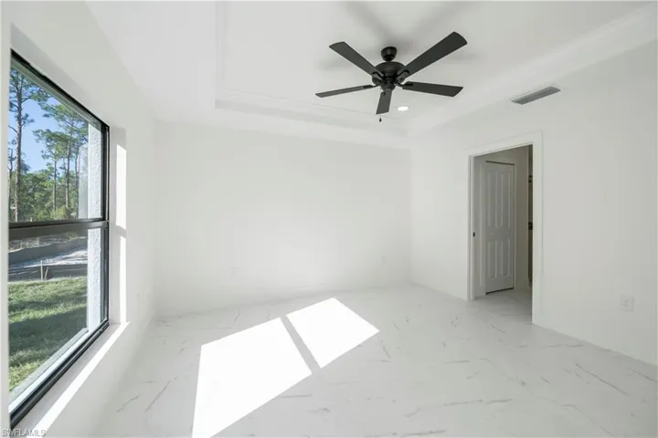 Empty room featuring ceiling fan, ornamental molding, and a tray ceiling