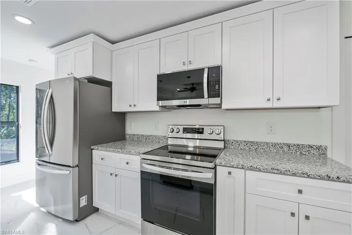 Kitchen featuring white cabinets, light stone counters, and appliances with stainless steel finishes