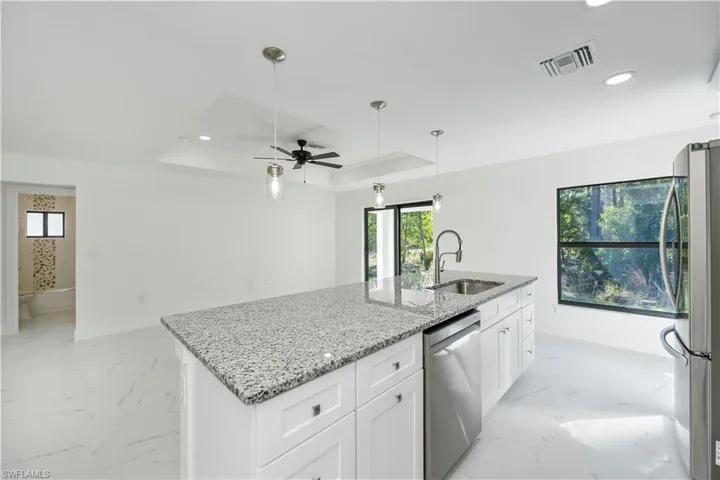 Kitchen featuring a center island with sink, sink, ceiling fan, white cabinetry, and stainless steel appliances