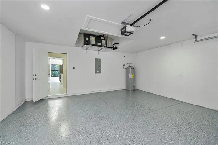 Garage featuring electric panel, water heater, and a garage door opener