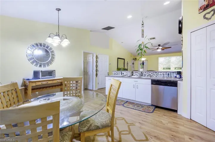 Dining area with ceiling fan with notable chandelier, light wood-type flooring, vaulted ceiling, and sink