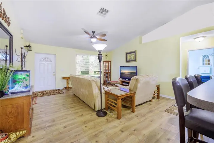 Living room featuring light vinyl hardwood  wood-style floors, ceiling fan, and vaulted ceiling