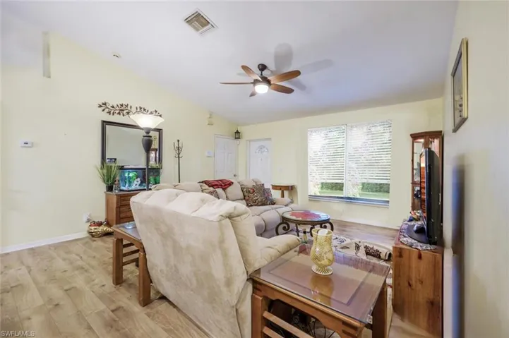 Living room featuring light vinyl hardwood  wood-style floors, ceiling fan, and vaulted ceiling