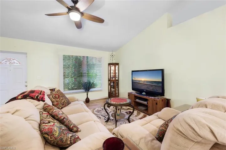 Living room with lofted ceiling  wood-style flooring, and ceiling fan