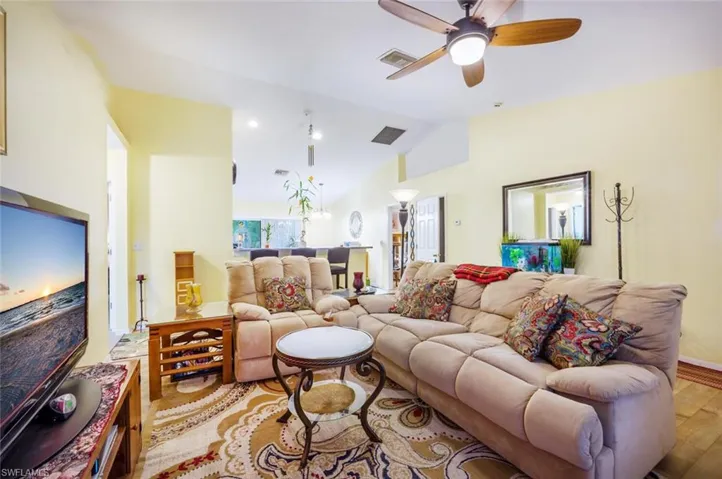 Living room featuring ceiling fan, light hardwood / wood-style floors, and lofted ceiling