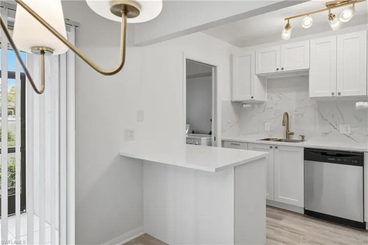 Kitchen featuring white cabinets, dishwasher, light wood-type flooring, and a peninsula
