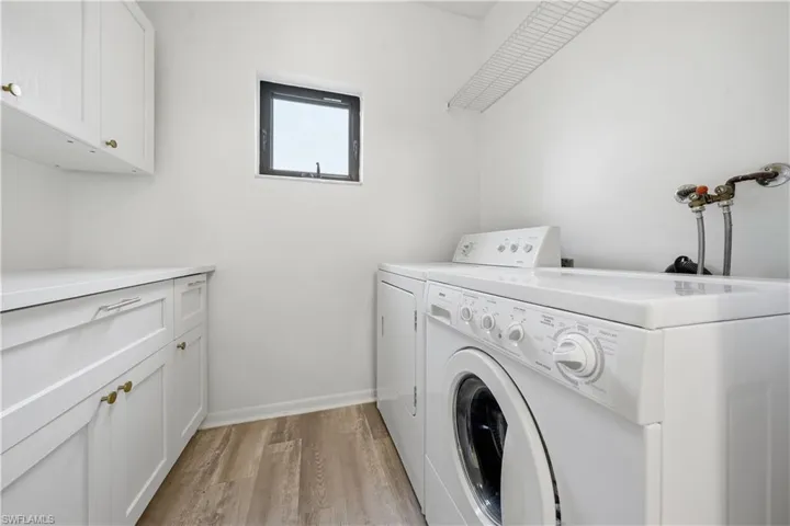 Laundry room featuring light wood-style flooring, separate washer and dryer, and cabinet space
