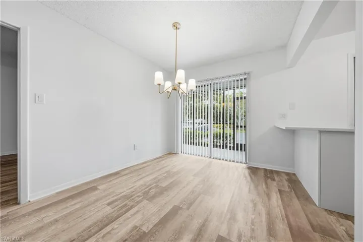 Unfurnished dining area with light wood finished floors, a textured ceiling, and a chandelier