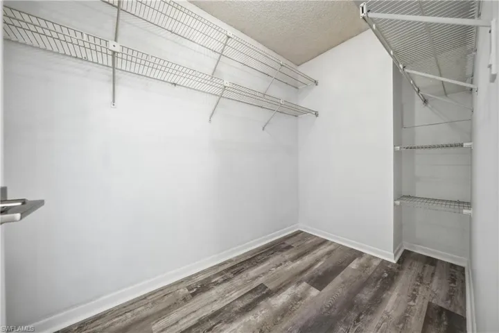 Walk in closet with dark wood-style flooring