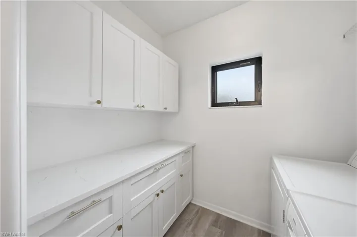 Laundry room with dark wood-type flooring, cabinet space, and washing machine and clothes dryer