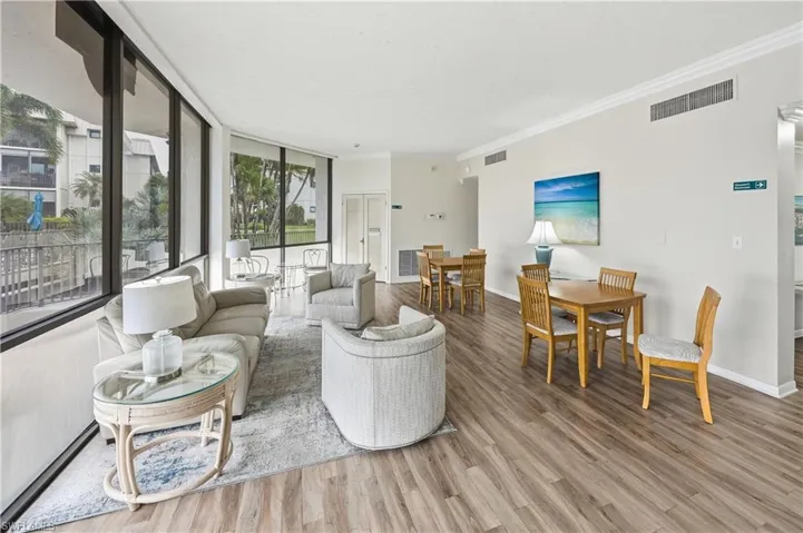 Living area featuring expansive windows, light wood-type flooring, and crown molding