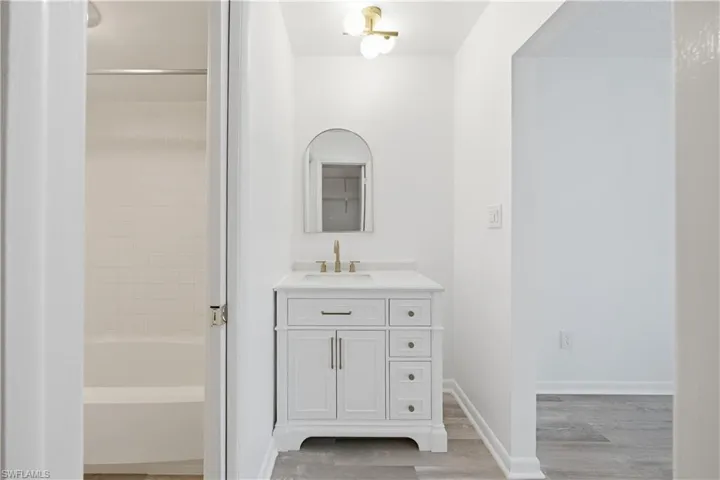 Full bathroom featuring vanity, light wood finished floors, and washtub / shower combination