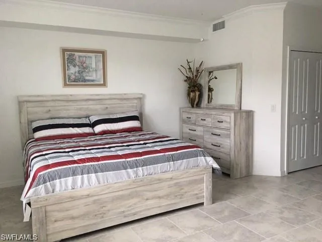 Bedroom with a closet, ornamental molding, and light tile patterned floors