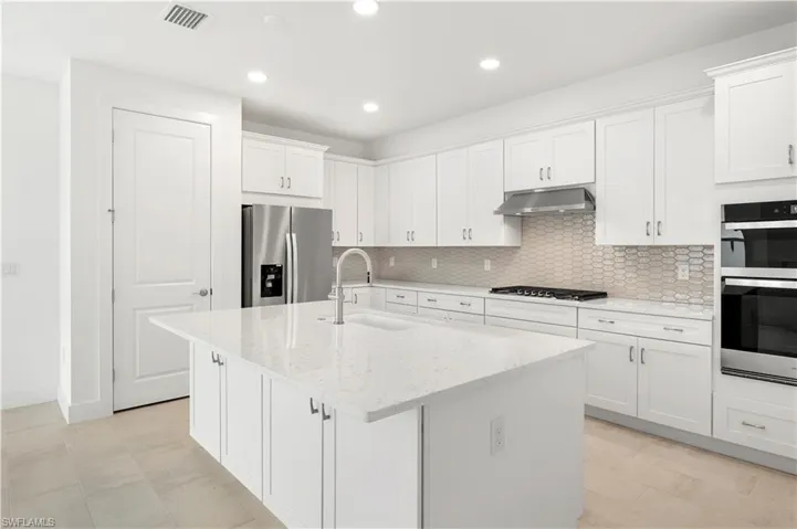 Stunning, kitchen layout with quartz countertops, ample cabinetry, and a suite of stainless steel appliances