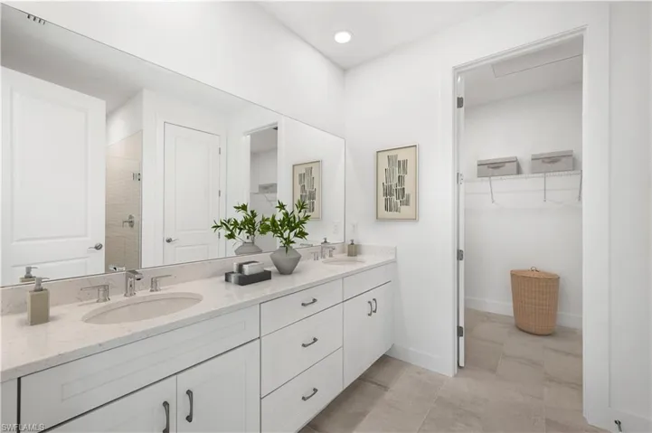 Primary bathroom with quartz countertops, wood cabinetry, and dual-sinks
