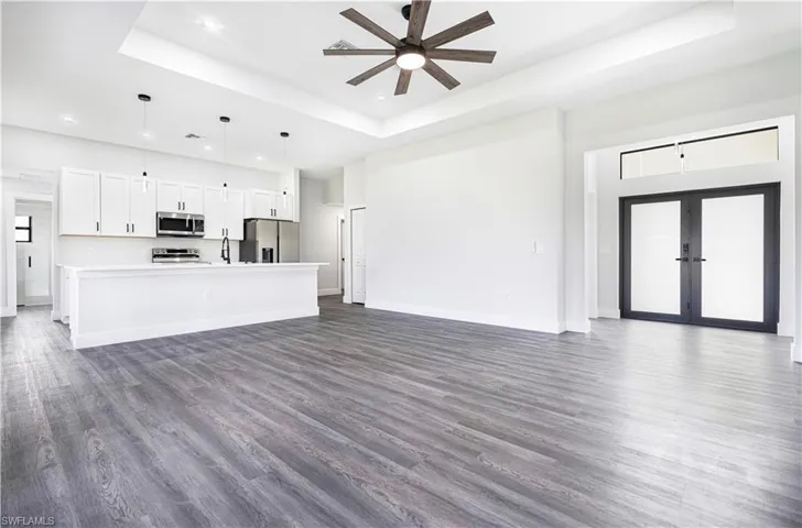 Unfurnished living room with french doors, a raised ceiling, ceiling fan, and dark hardwood / wood-style flooring