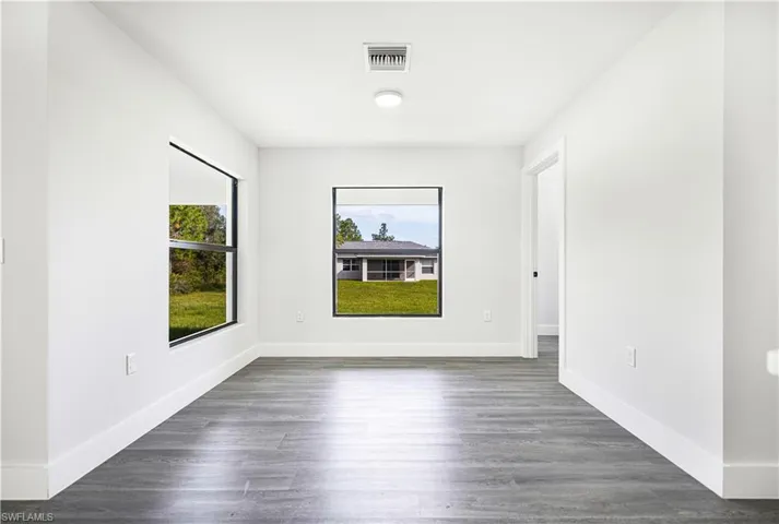 Empty room with dark hardwood / wood-style floors and a healthy amount of sunlight