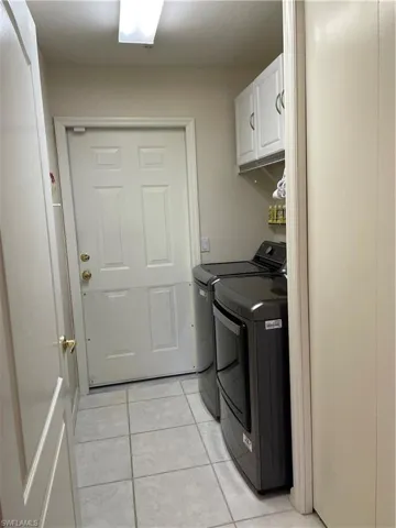 Laundry area featuring cabinets, washer and dryer, and light tile patterned floors