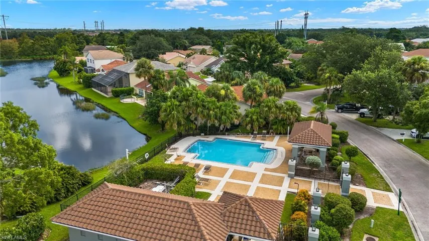 Aerial perspective of suburban area featuring a pool and a large body of water