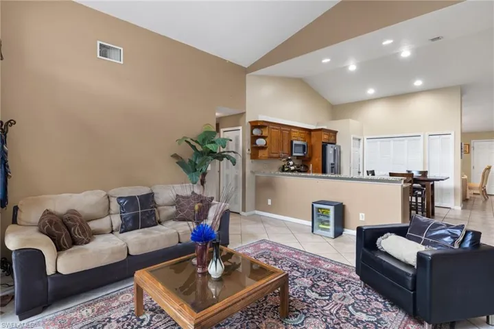Living area featuring light tile patterned flooring, high vaulted ceiling, and recessed lighting