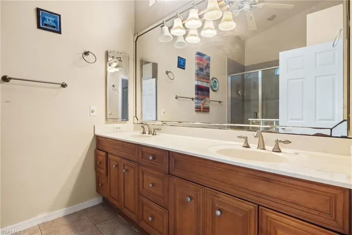 Full bath with a stall shower, light tile patterned floors, and double vanity