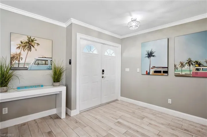 Entrance foyer with light wood finished floors and crown molding