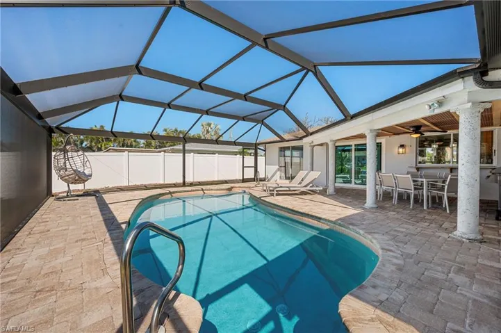 View of pool with glass enclosure, a patio area, a sunroom, and outdoor dining space