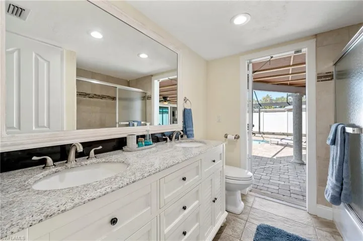 Bathroom with a tile shower, double vanity, recessed lighting, plenty of natural light, and light tile patterned flooring