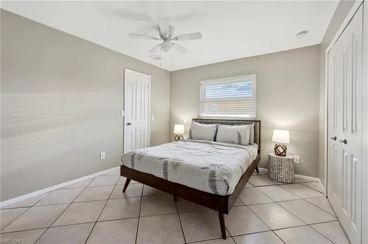 Bedroom featuring a closet, light tile patterned floors, and ceiling fan