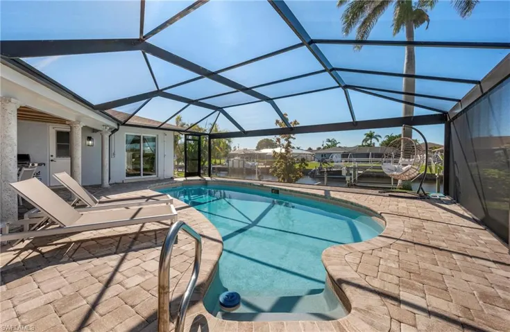 Swimming pool with a sunroom, a patio, glass enclosure, and a water view