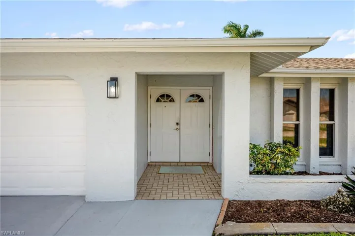 Property entrance with stucco siding, a garage, and a shingled roof