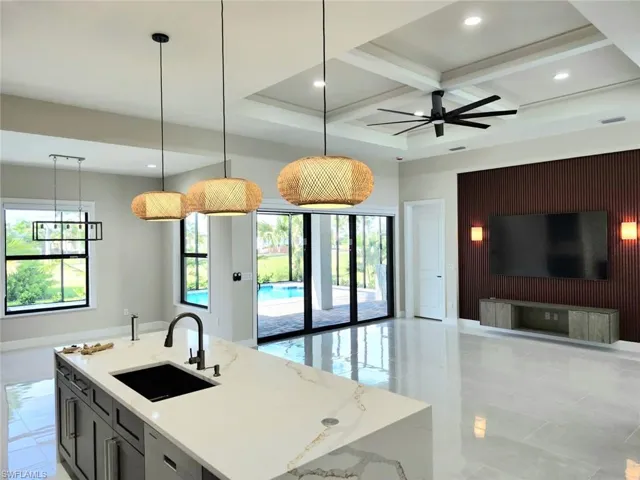 Kitchen featuring beamed ceiling, sink, light stone countertops, ceiling fan, and coffered ceiling