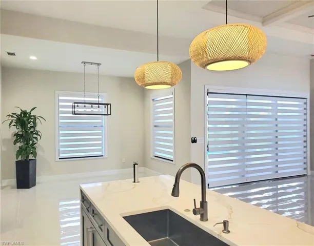 Kitchen with sink, pendant lighting, a healthy amount of sunlight, and light stone counters