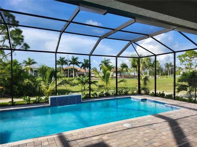 View of pool with pool water feature, glass enclosure, and a patio area