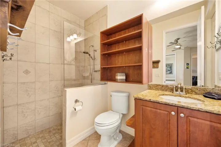 Bathroom with vanity, walk in shower, ceiling fan, and light tile patterned floors