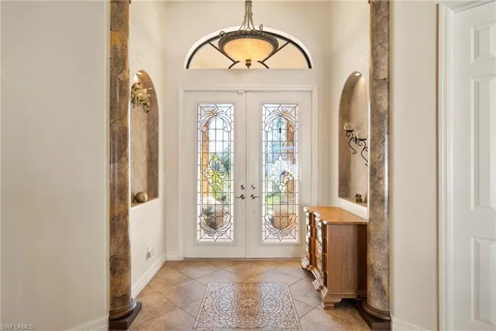 Entrance foyer featuring light tile patterned flooring, french doors, and inlaid floor details