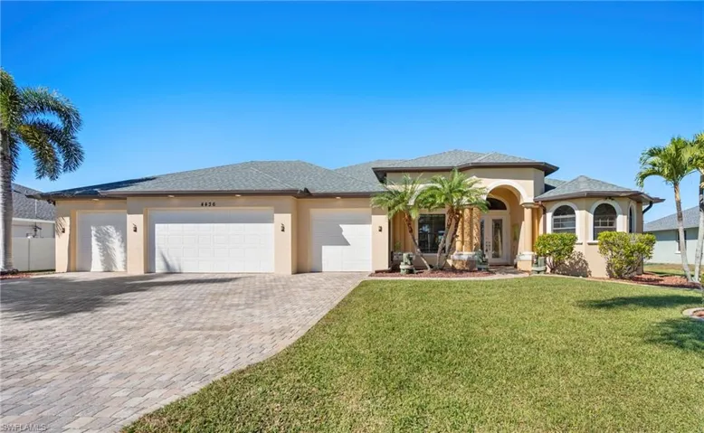 View of front of property featuring an attached garage, decorative driveway, stucco siding, and a front lawn