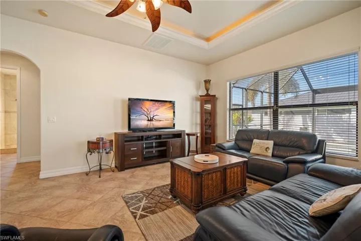 Living room featuring arched walkways, ceiling fan, and ornamental molding