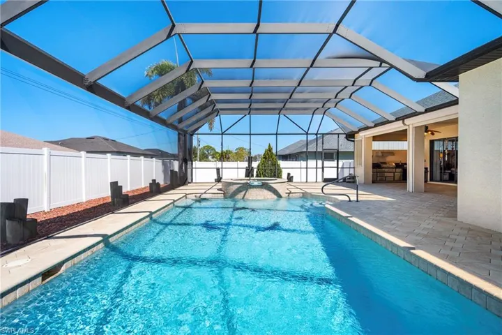 Combined pool / hot tub featuring a patio area, a fenced backyard, a sunroom, and glass enclosure