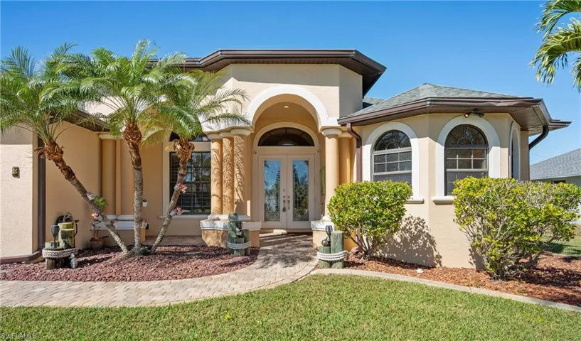 Entrance to property featuring french doors, stucco siding, and a lawn